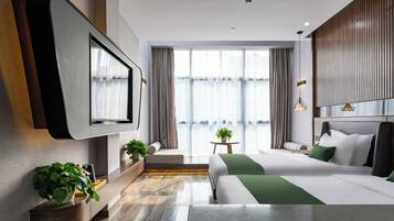 Una habitación de hotel moderna con televisión de pantalla plana, un sofá, una cama, una mesita con una planta y vistas al exterior.