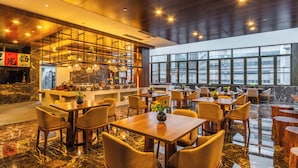 A modern restaurant with a bar area, multiple dining tables, and chairs. - Immersing Hotel (Chengdu)