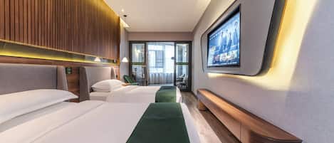 Habitación de hotel con dos camas, televisión y vistas al exterior.