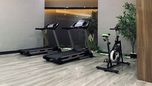 A gym with treadmills, a stationary bike, and a wall-mounted screen. - Immersing Hotel (Chengdu)