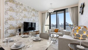 Un salon moderne comprenant un coin repas, un téléviseur à écran plat et une vue sur la ville.