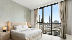 Une chambre d’hôtel moderne dotée d’un grand lit, d’une table de chevet, d’un bureau et offrant une vue sur le paysage urbain.