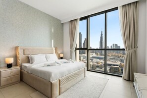 Ein modernes Hotelzimmer mit einem großen Bett, einem Nachttisch, einem Schreibtisch und Blick auf eine Stadtlandschaft.
