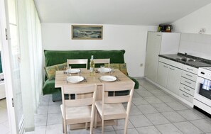 A compact kitchen with a dining table set for two, a green sofa, and a painting on the wall. - Prime location apartment nicely equipped (Zambratija)