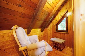 A wooden cabin interior with a single wooden chair and bench, a window, and a sloped ceiling. - Vacation home in the countryside - natural idyll with whirlpool & pool for 4-5 people (Breze)