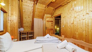 Ein Zimmer einer Holzhütte mit zwei Betten, einer Holzzahlung und einer Tür zu einem anderen Raum.