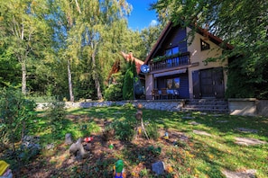 A house with a balcony, surrounded by trees and a garden. - Vacation home in the countryside - natural idyll with whirlpool & pool for 4-5 people (Breze)