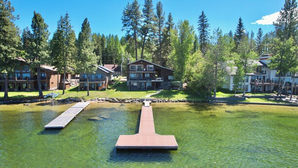 Un complexe hôtelier au bord d’un lac, doté de quais en bois, de bâtiments à plusieurs étages et entouré d’une forêt.