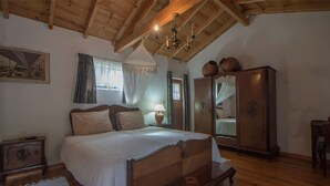 Ein Schlafzimmer mit Holzbalkendecke, einem Himmelbett, einem Kleiderschrank und einem Bild an der Wand.