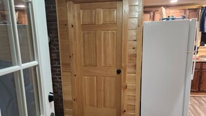 Een houten deur, een witte koelkast en een kamerkleed met een patroon in een keuken.
