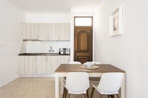A compact kitchen with white cabinets, a wooden table, and two white chairs. - Las Américas lovely pool view (Arona)