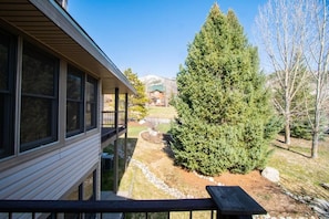 Ein Wohnhaus mit Balkon, einem großen immergrünen Baum und freiem Blick auf einen Berg im Hintergrund.