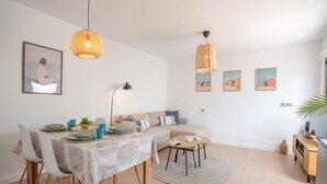 Ein stilvolles Wohnzimmer mit Essbereich, einer Couch, einem Couchtisch und Kunstwerken an den Wänden.