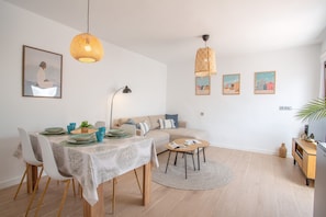 Ein stilvolles Wohnzimmer mit Essbereich, einer Couch, einem Couchtisch und Kunstwerken an den Wänden.