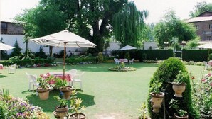 A well-maintained garden with outdoor seating, potted plants, and a clear pathway. - Hotel Meridien River Front Rajbagh (Srinagar)