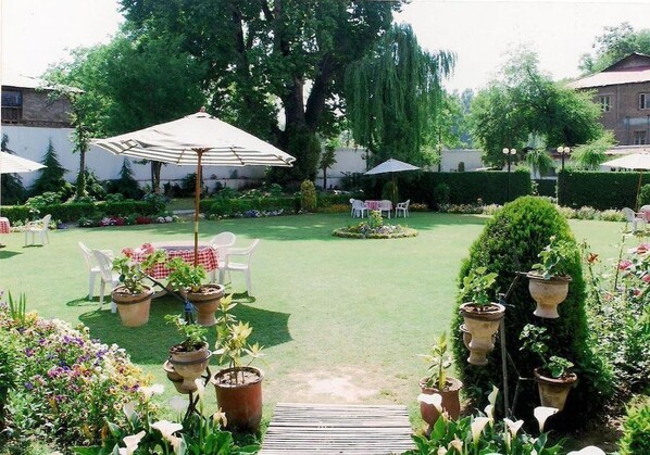 A well-maintained garden with outdoor seating, potted plants, and a clear pathway. - Hotel Meridien River Front Rajbagh (Srinagar)