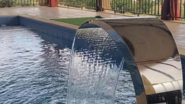 Ein Outdoor-Whirlpool mit Wasserfall, umgeben von einer überdachten Terrasse mit Blick auf die Landschaft.