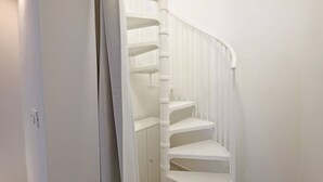 A white spiral staircase with a handrail, leading to a landing with a door. - Dimor Monolocale Deluxe (Casarano)
