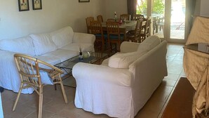 A living room with a sofa, chairs, a dining table, and a view through a glass door. - Villa Spacieuse Avec Piscine Priv e 150 m de la Plage Calvi Centre (Calvi)