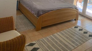 A bedroom with a bed, a chair, a lamp, and a door leading outside. - Villa Spacieuse Avec Piscine Priv e 150 m de la Plage Calvi Centre (Calvi)