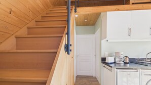 A wooden staircase leading to a loft bedroom with a view of a kitchen area. - 700m from the sea, chalet for 2 (Andernos-les-Bains)