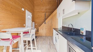 A compact kitchen with a wooden interior, a sink, a washing machine, and a dining area with chairs. - 700m from the sea, chalet for 2 (Andernos-les-Bains)
