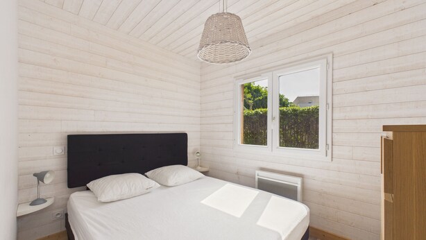 A bedroom with a bed, a window, a radiator, and a hanging light fixture. - 700m from the sea, chalet for 2 (Andernos-les-Bains)