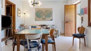 Un comedor con una mesa y sillas de madera, un mapa-globo en la pared y un televisor sobre un mueble.