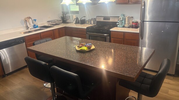 A modern kitchen with a central island, bar stools, stainless steel appliances, and pendant lighting.