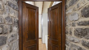Une porte en bois qui donne sur une pièce aux murs de pierre et au sol carrelé.