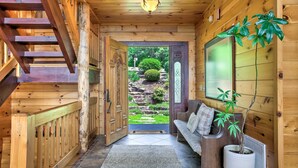 Interior de madera con una escalera, un banco y una planta en maceta.