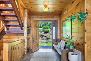 A wooden interior with a staircase, a bench, and a potted plant.