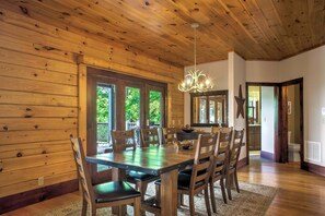 A wooden-paneled dining room with a chandelier, a large mirror, and a view of the outdoors.