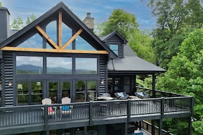 Una cabaña de madera con balcón, ventanas amplias y mobiliario de exterior.