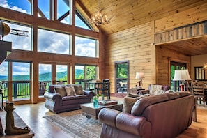Un interior espacioso de madera con amplias ventanas, una chimenea y un comedor.