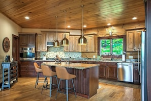 A kitchen with wooden cabinets, stainless steel appliances, and a large island with bar stools.
