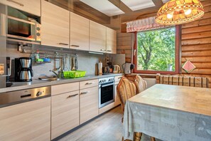 Een moderne keuken met houten kastjes, een inbouwoven en een eethoek met een tafel en stoelen.