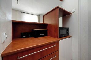 A compact kitchenette with a microwave, a bread box, and sugar and tea containers. - Functional Studio in the Center | Close to the Market | Smart TV (Wrocław)