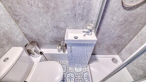 Een badkamer met toilet, wastafel en douche.