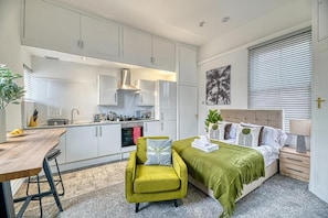 A compact bedroom with a bed, bedside table, and a green chair.