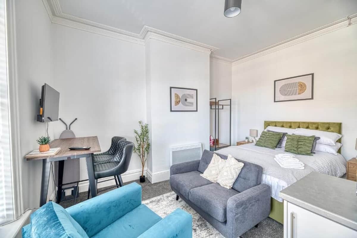 Una habitación de hotel moderna con una cama, un escritorio, un sofá y un televisor.