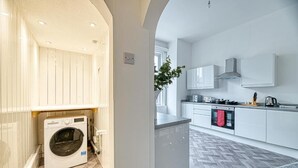 Een moderne keuken met een ingebouwde wasmachine, witte kasten en een visgraatvloer.