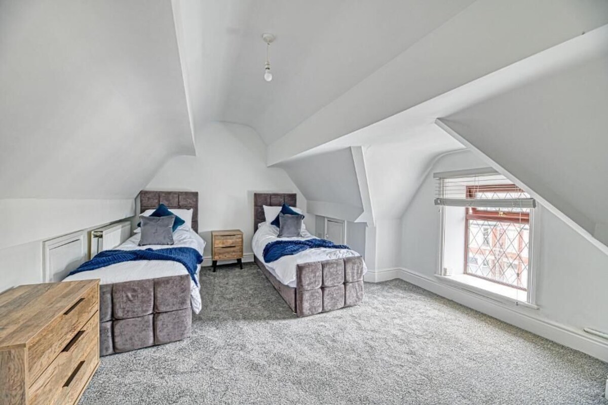 Un dormitorio con dos camas, un aparador de madera y un ventanal con vistas.