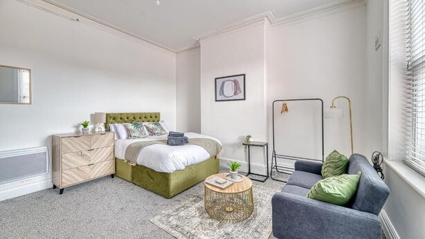 Een slaapkamer met een bed, een dressoir, een nachtkastje en een bank.