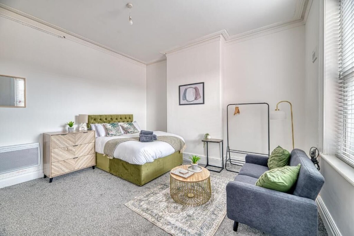 Un dormitorio con cama, cómoda, mesita de noche y sofá.