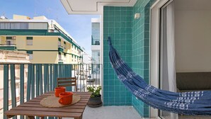 En balkon med en hængekøje, et bord med to orange krus og en potteplante.