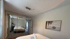 A bedroom with a bed, a large mirror, a painting, and a wardrobe. - Chic Waterfront Stay with Prime Sydney Access (Lavender Bay)