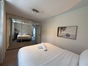 A bedroom with a bed, a large mirror, a painting, and a wardrobe. - Chic Waterfront Stay with Prime Sydney Access (Lavender Bay)