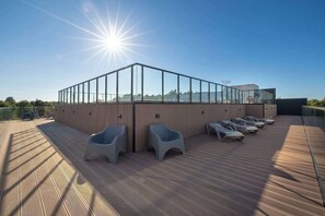 Terraza soleada con sillones de descanso y cerramiento de cristal.