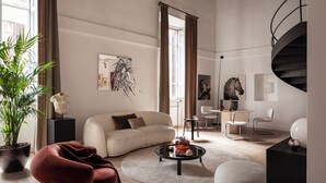 A modern living room with a sofa, coffee table, and chairs, a staircase, and a large plant. - Luxury apartment near the Spanish Steps (Roma)